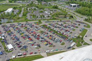 A large parking lot filled with various cars and green surroundings.