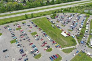 Aerial view of a parking lot with cars and a highway nearby.