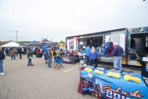 People shopping at an outdoor market with various booths and merchandise.