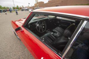 Interior view of a classic red car with black seats and steering wheel.