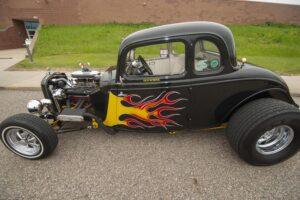 Classic black hot rod with vibrant flame decals and exposed engine.