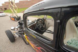 Classic black hot rod car with flame decals and vintage interior.