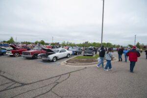 People walking among classic cars at an outdoor car show.