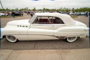 Classic white convertible car parked outdoors on a cloudy day.