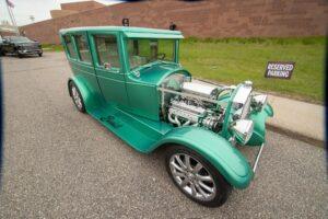 Vintage green car with exposed engine and shiny chrome details.