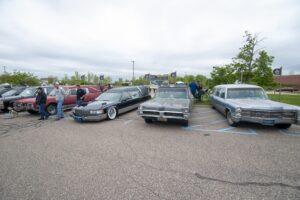 Three classic cars parked side by side at an outdoor event.