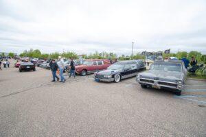 A lineup of vintage cars parked outdoors with people admiring them.