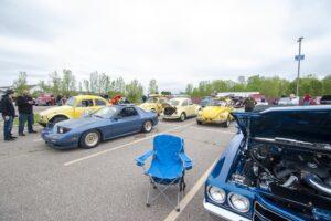 Classic cars parked at an outdoor car show on a cloudy day.