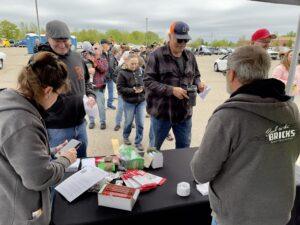People gather at an outdoor event, signing autographs and socializing.
