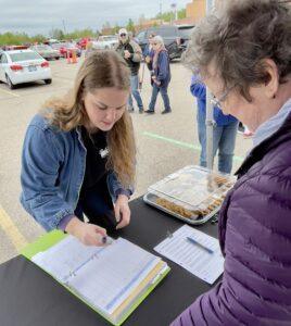 Two women engaged in a registration or sign-up process outdoors.