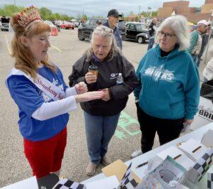 Three women engaged in conversation outdoors, reviewing documents.