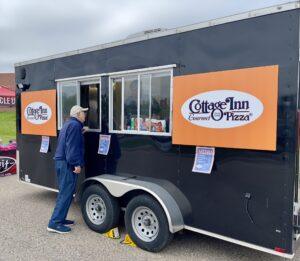 A person ordering food at a Cottage Inn Pizza food truck.