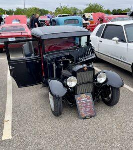 A black vintage car with open doors at a car show.