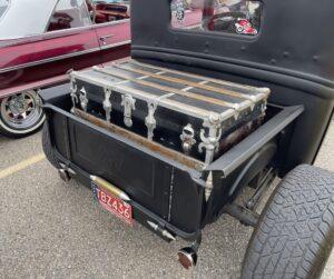 Vintage car with classic luggage trunk on rear, showcasing nostalgic travel style.