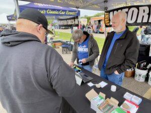 People browsing vintage comic books and collectibles at an outdoor market stall.