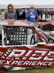 Race car driver in a red and white car at a motorsport event.