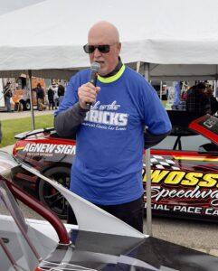Man wearing sunglasses and a blue "I Love Trucks" shirt speaking into a microphone.