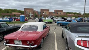 A classic car show with vintage vehicles parked under a cloudy sky.