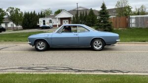 Classic blue muscle car parked on a suburban street during daytime.