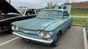 Vintage teal Chevrolet Corvair parked outdoors.