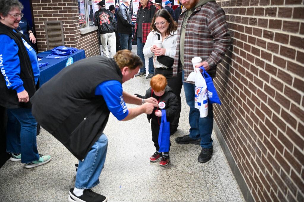 A young child receives a gift from a man while adults look on nearby.