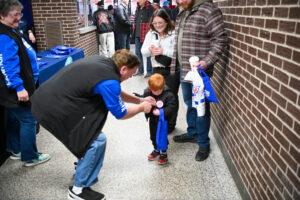 A young child receives a gift from a man while adults look on nearby.