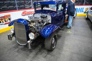 A shiny blue vintage hot rod car on display at a car show.