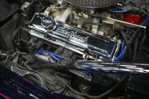 Close-up of a shiny chrome engine valve cover in a car engine bay.