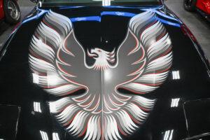Close-up of a silver phoenix emblem on a black background.