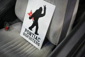 A humorous Pontiac Bigfooters sticker on a car seat.