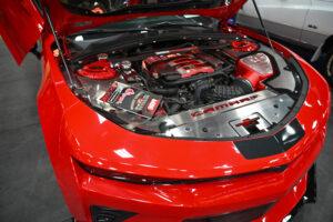 Close-up of a red sports car engine bay with detailed components and branding.