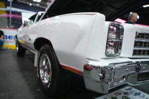 Close-up of a classic white car's rear wheel and tail light with chrome details.