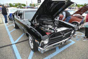 Classic black muscle car with its hood open, showcasing a detailed engine.