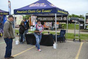 Volunteer standing at a classic car event check-in booth.