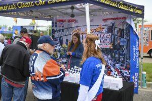 Two fans shopping for sports merchandise at an outdoor booth.