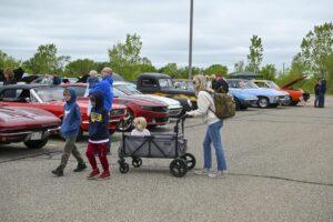 Family walking together at a car show with a wagon full of supplies.