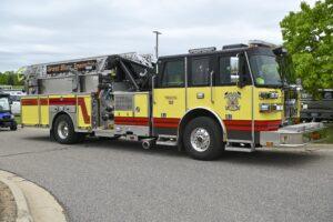 Yellow fire truck parked on a road under a cloudy sky.