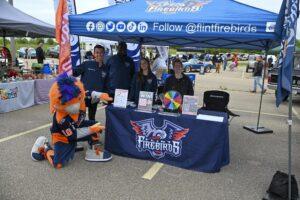 People at a community event booth for the Flint Firebirds hockey team.