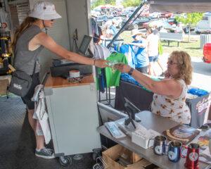 A woman serves a green drink to a customer at an outdoor bar stall.