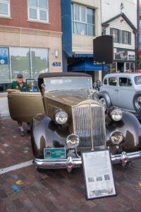 Classic vintage car displayed at a car show with informational plaque.