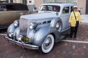 A classic silver vintage car parked on a brick street.