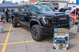 Black GMC Sierra pickup truck parked at an outdoor event.
