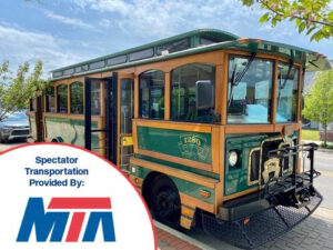 A vintage-style green trolley bus parked outdoors on a sunny day.