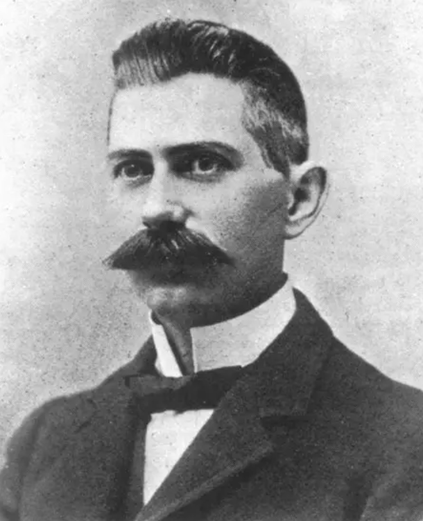 Man with mustache in vintage formal attire.
