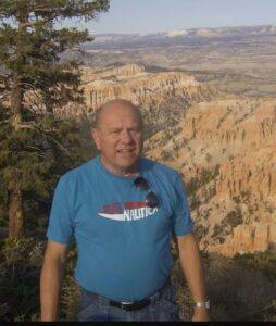 Man in blue shirt at scenic canyon.