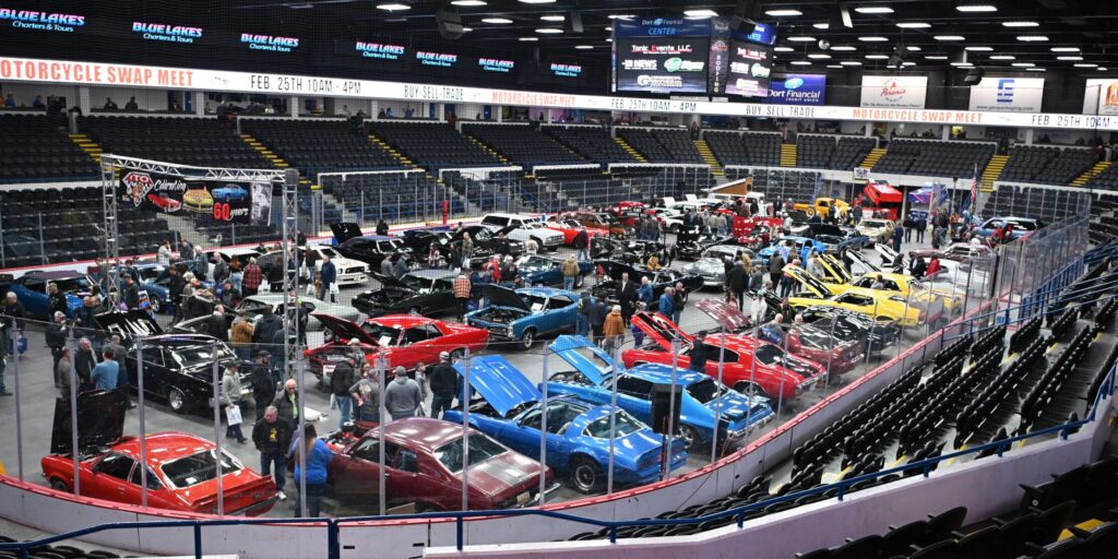 Car exhibition in large indoor arena setting.