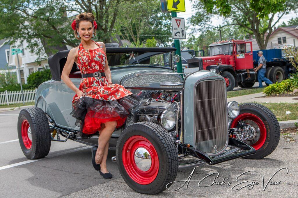 Woman in vintage dress on classic car.