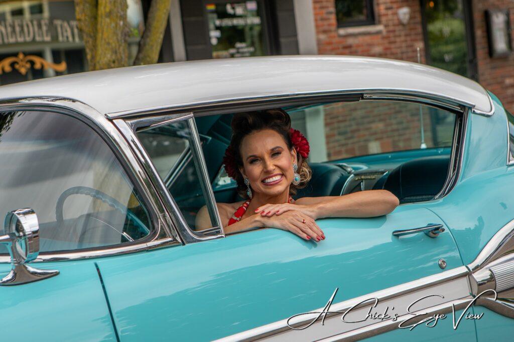 Woman smiling from vintage turquoise car window.