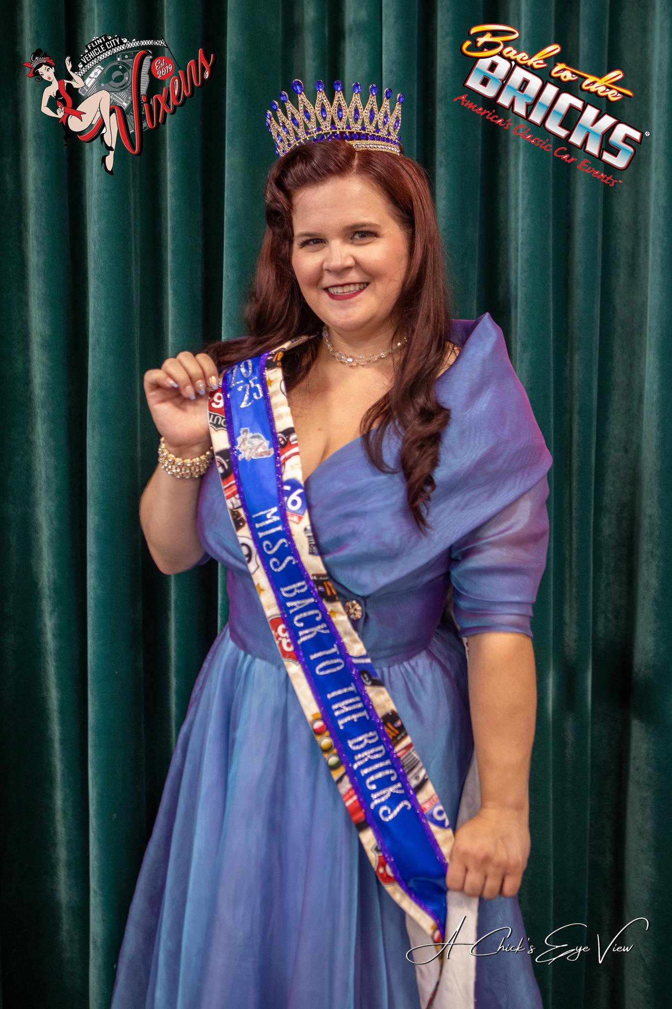 Woman in blue gown with crown and sash.
