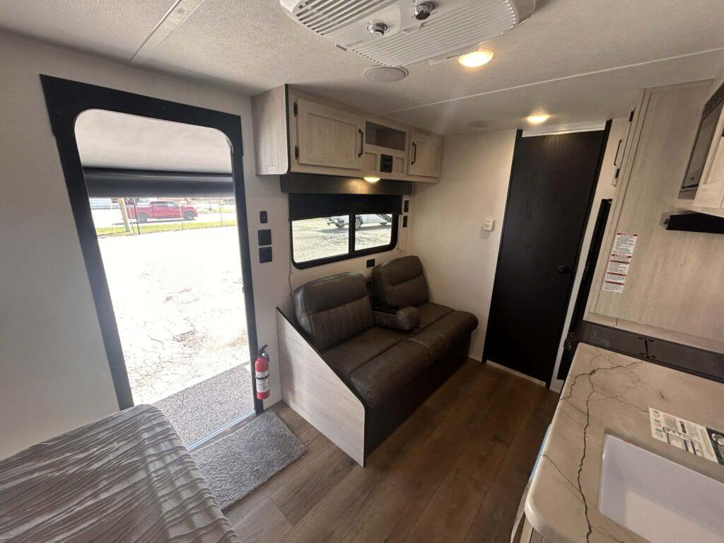RV interior with sofa and open door.